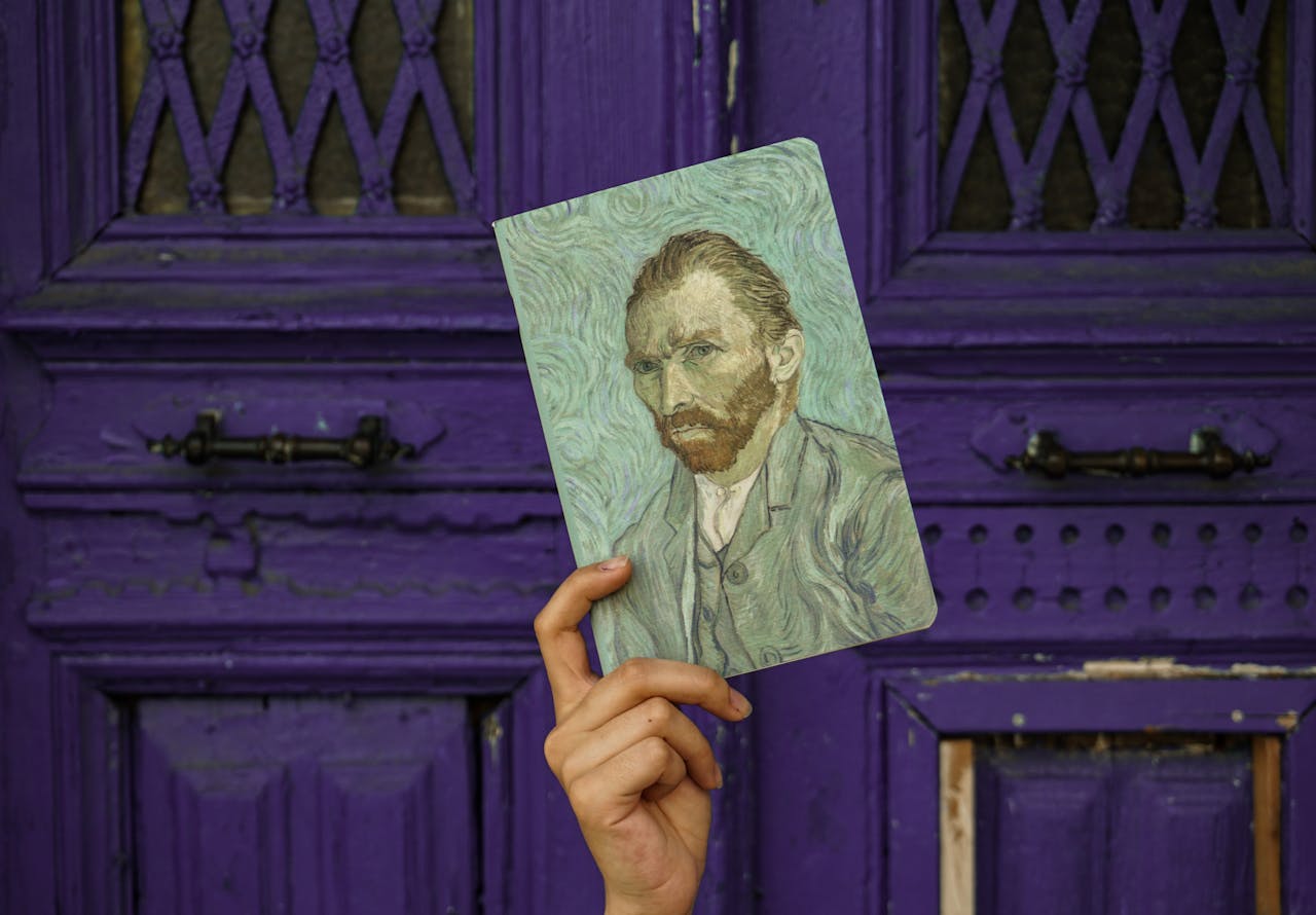 menu-02 A hand holding a Van Gogh self-portrait against a textured purple door background.